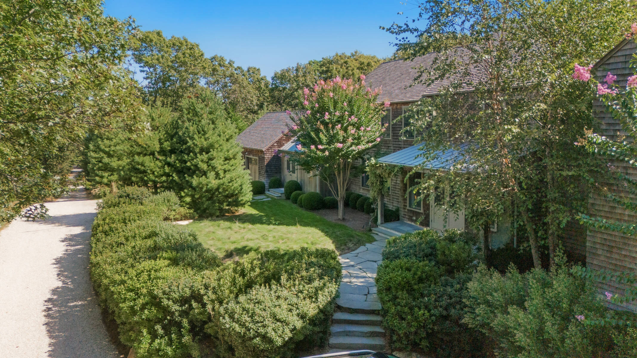 outdoor of shingle-style home with verdant landscaping and stone path