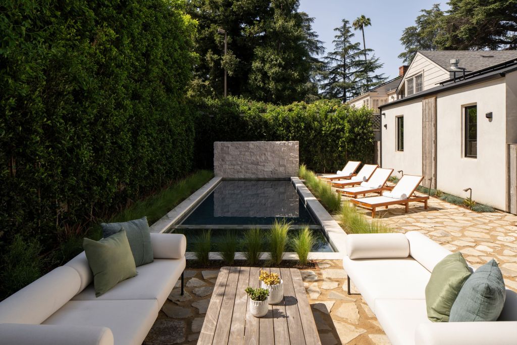 outdoor courtyard with seating, pool, and hedge wall