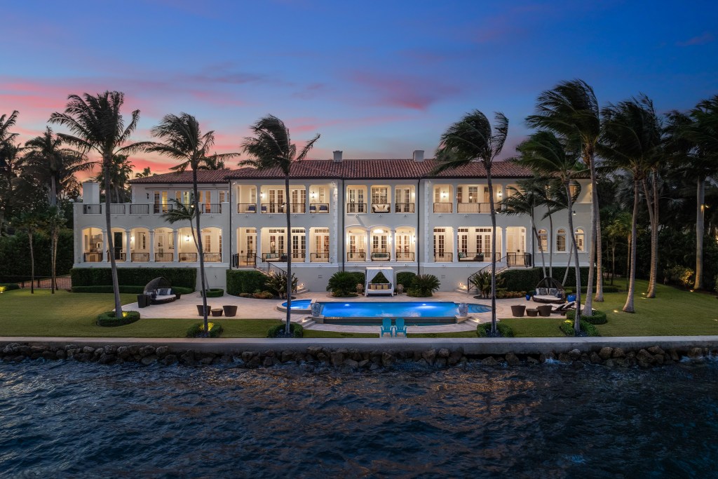 exterior of waterfront home in Coral Gables, Florida with swaying palm trees at sunset