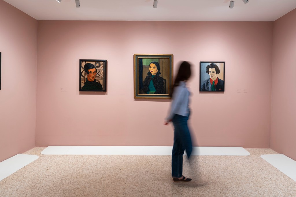 person walking through a gallery of Peggy Guggenheim's collection of portraits