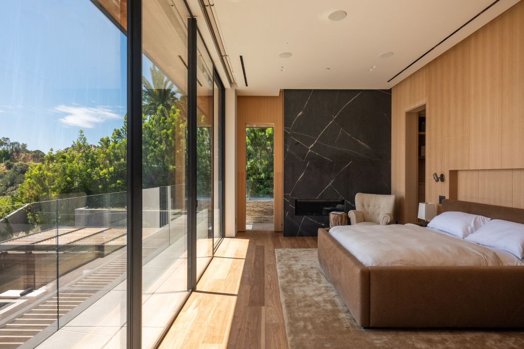 primary bedroom with walls of glass and marble slab fireplace