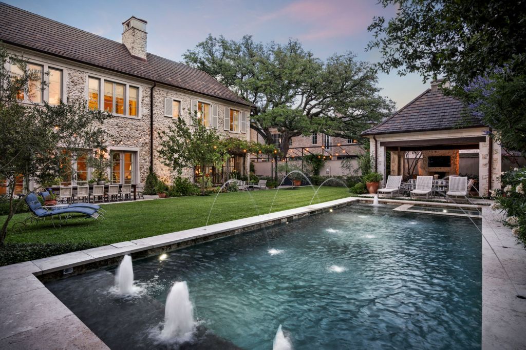 pool with multiple fountains behind a stone manor house in Texas