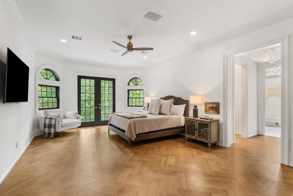 primary suite bedroom with french doors and herringbone parquet floors