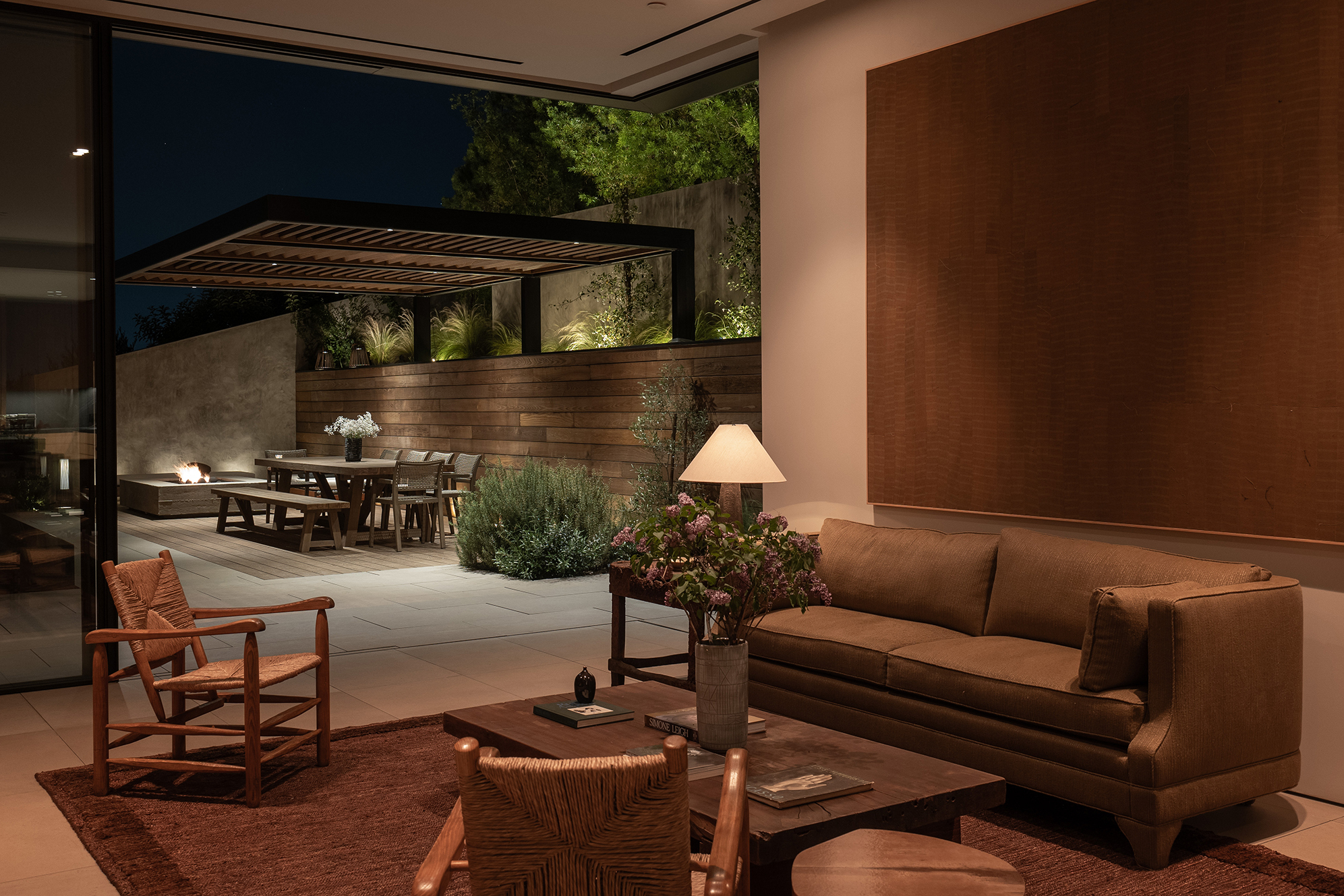 interior living room with large glass walls and doors opening to a terrace with dining table