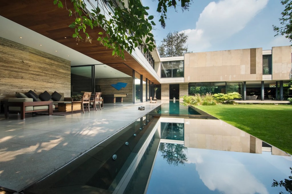 Contemporary home exterior in Mexico City with glass walls, waterfall-edge pool and terraces