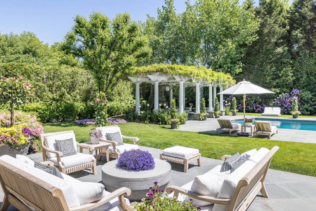 outdoor seating area near pool deck and pergola immersed in flowers and greenery