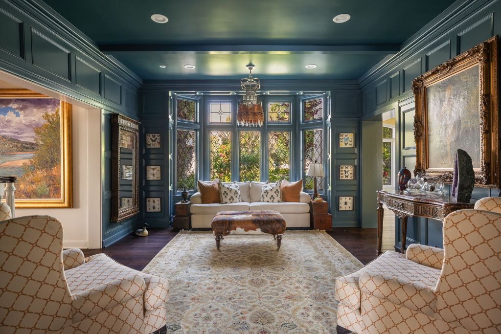 teal sitting room with bay window in Tudor-style Los Angeles home