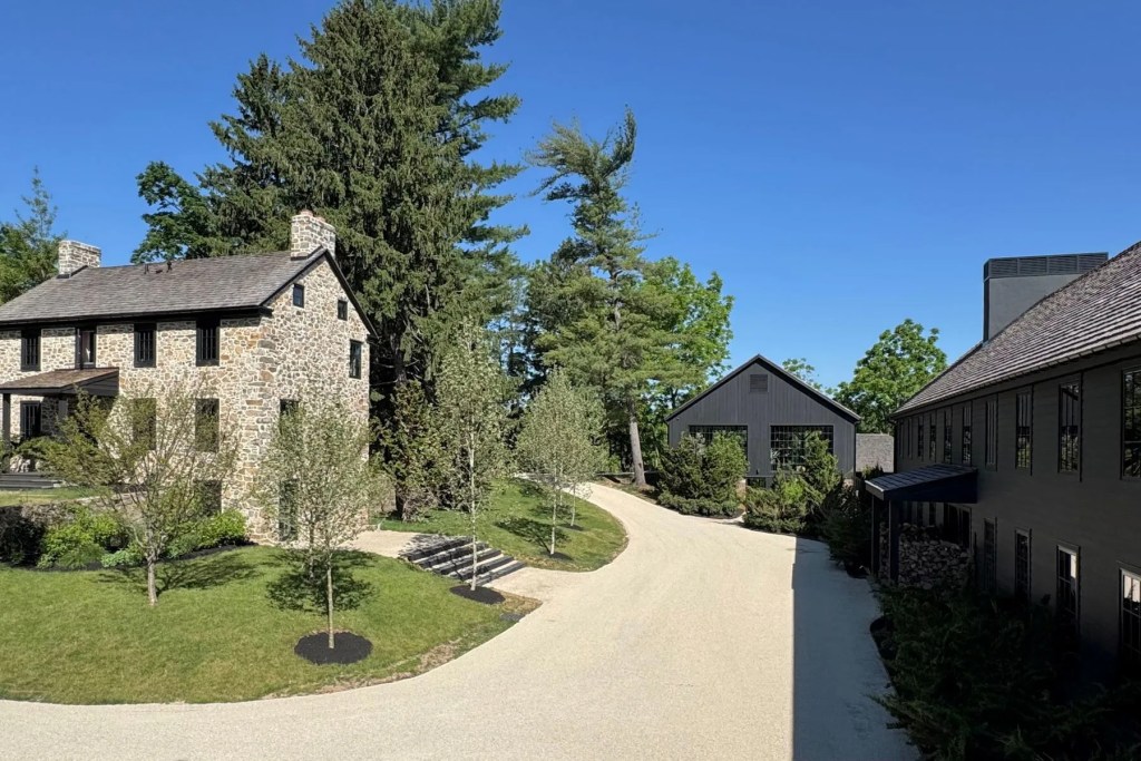 Stone house and two modern buildings in New Hope, Pennsylvania, connected by gravel and a grass lawn, with trees in the background.
