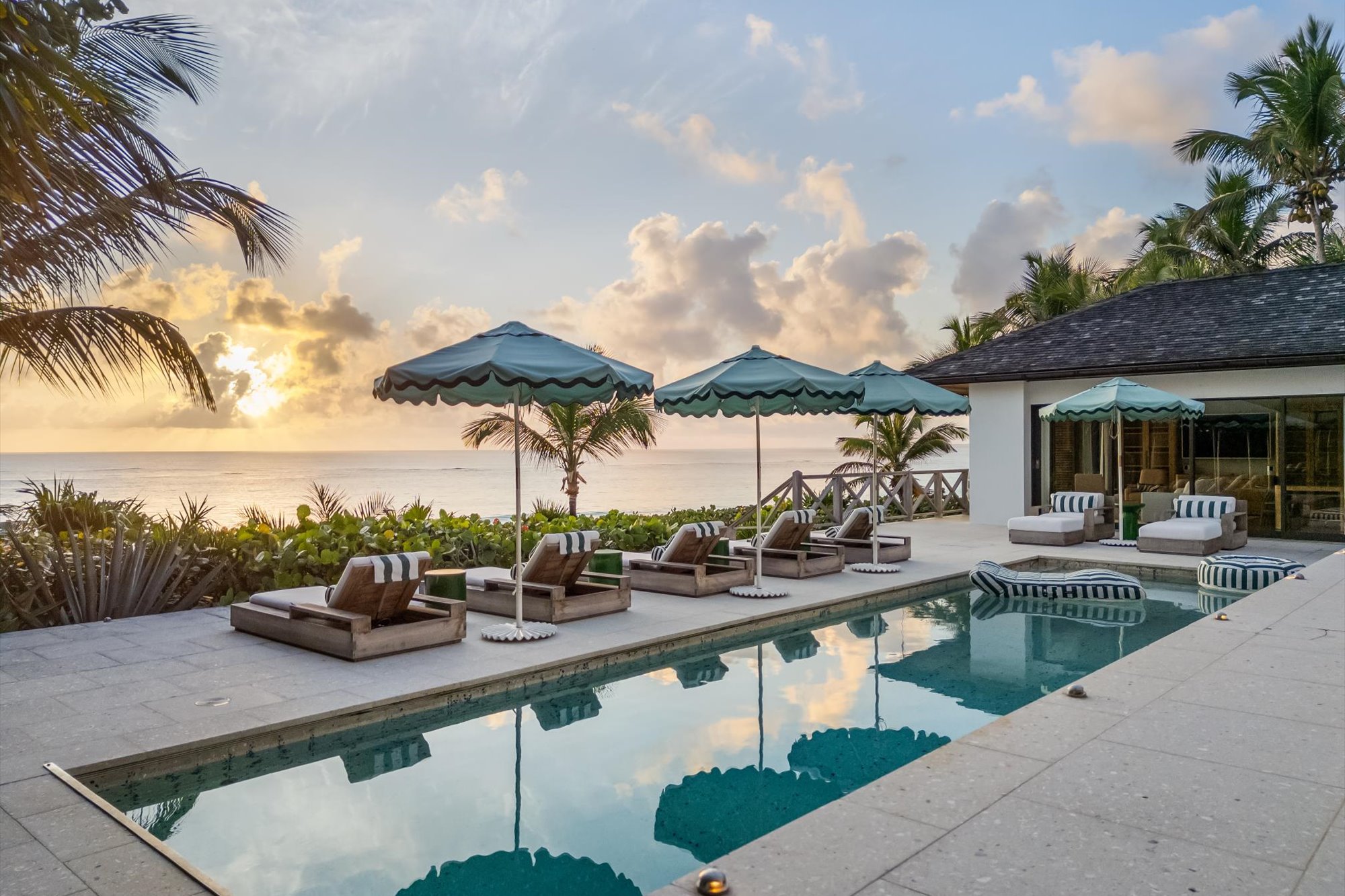 Pool and patio with deck chairs and umbrellas in Harbour Island, the Bahamas, looking out to ocean views.