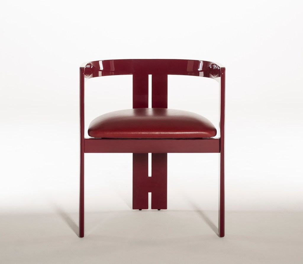 Front view of a burgundy chair with a curved backrest, upholstered seat cushion, and geometric wood frame against a white background.