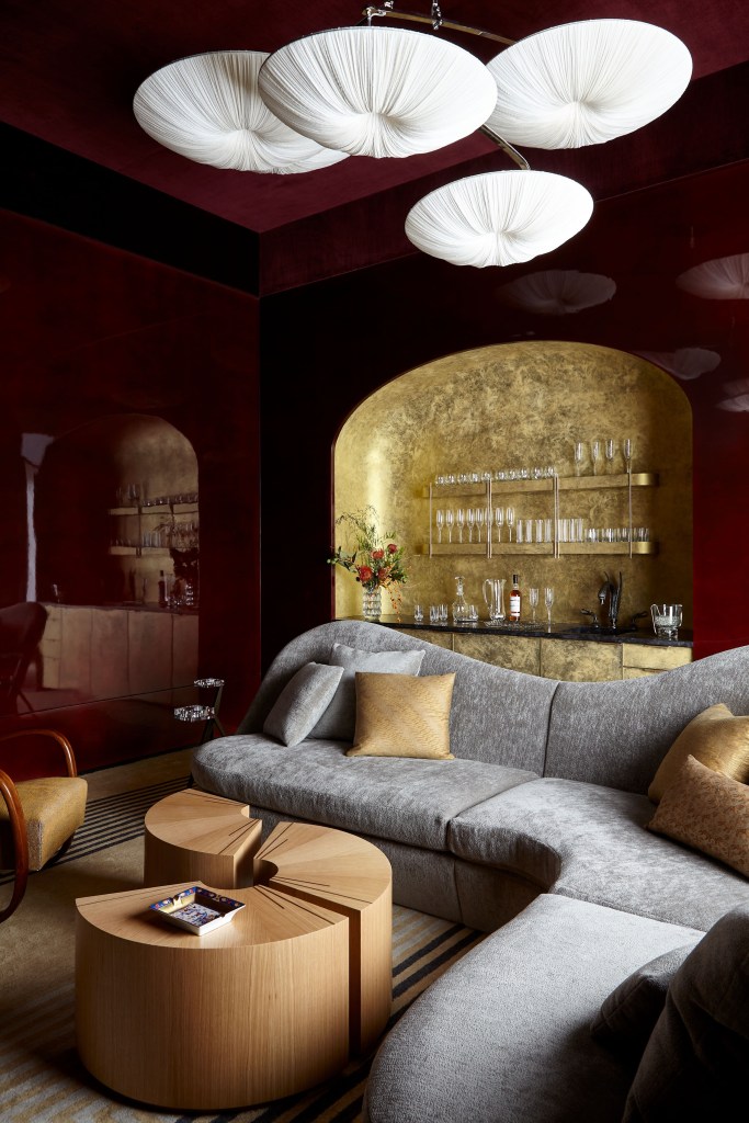 gold wet bar in Tribeca by Hines Collective with statement coffee table and grey couch in the foreground