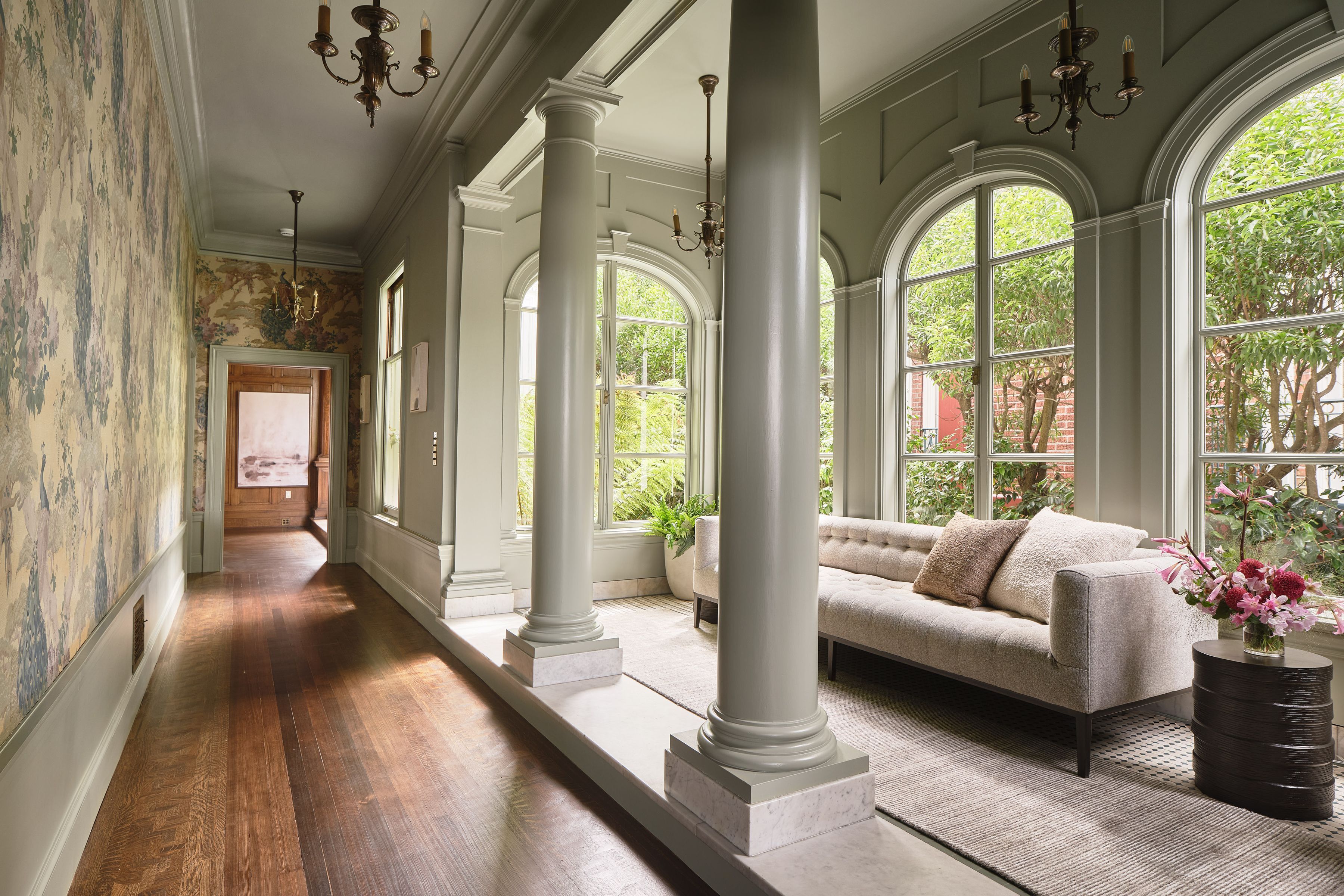 interior hallway with sunroom in Presidio Heights home, featuring botanical wallpaper, columns, and plush seating