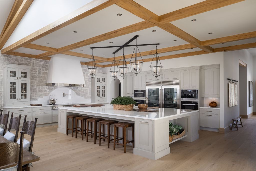 chef's kitchen in Maison de Campagne with large marble-topped island, dual refrigerators, and stone oven backsplash 