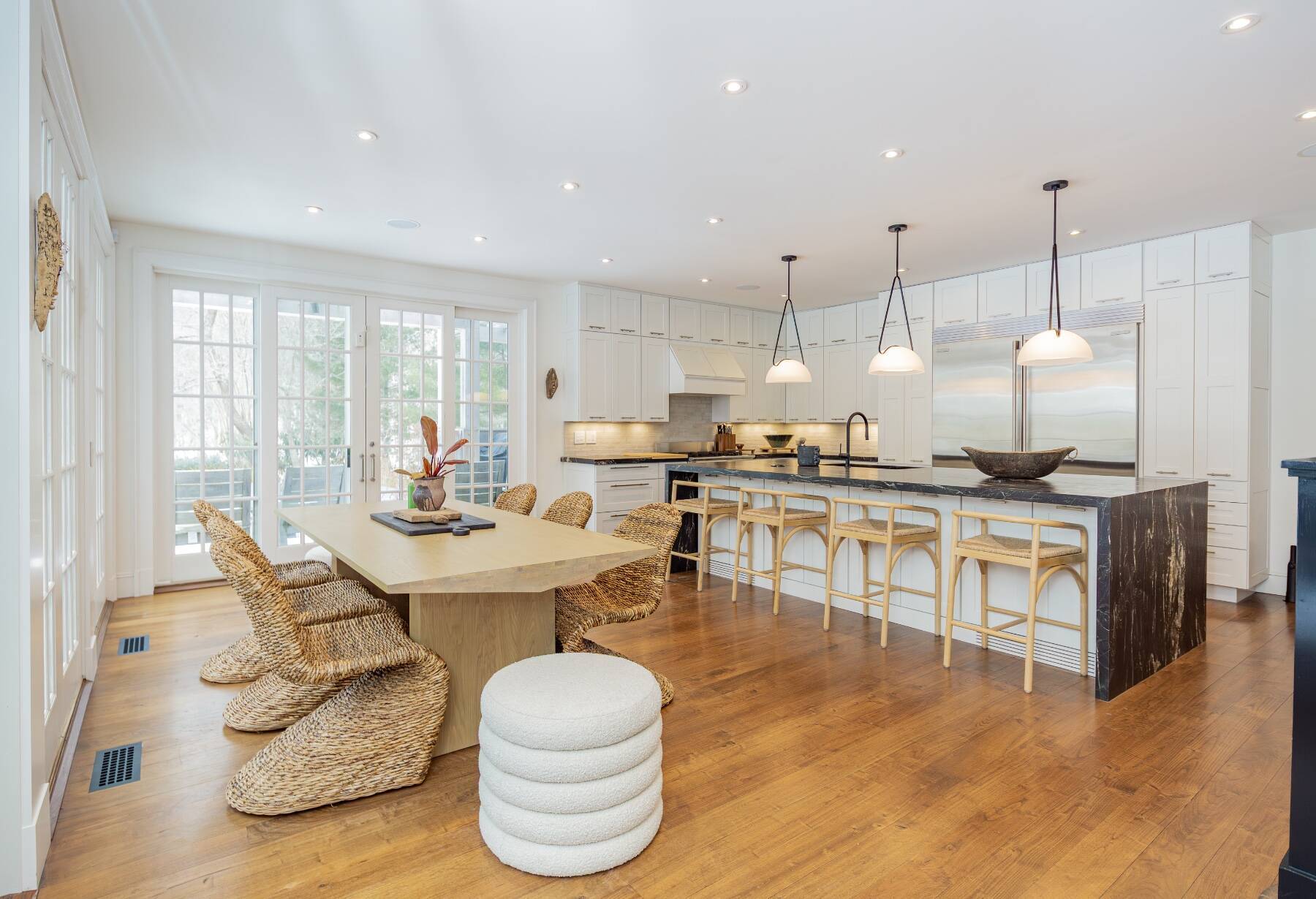 interior kitchen and dining area in Amagansett, NY home with waterfall edge island with barstools and dining table with chairs