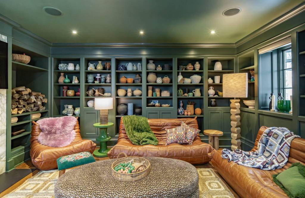 sitting room with forest green built-in shelving featuring pottery with leather chair and sofas and a large central coffee table