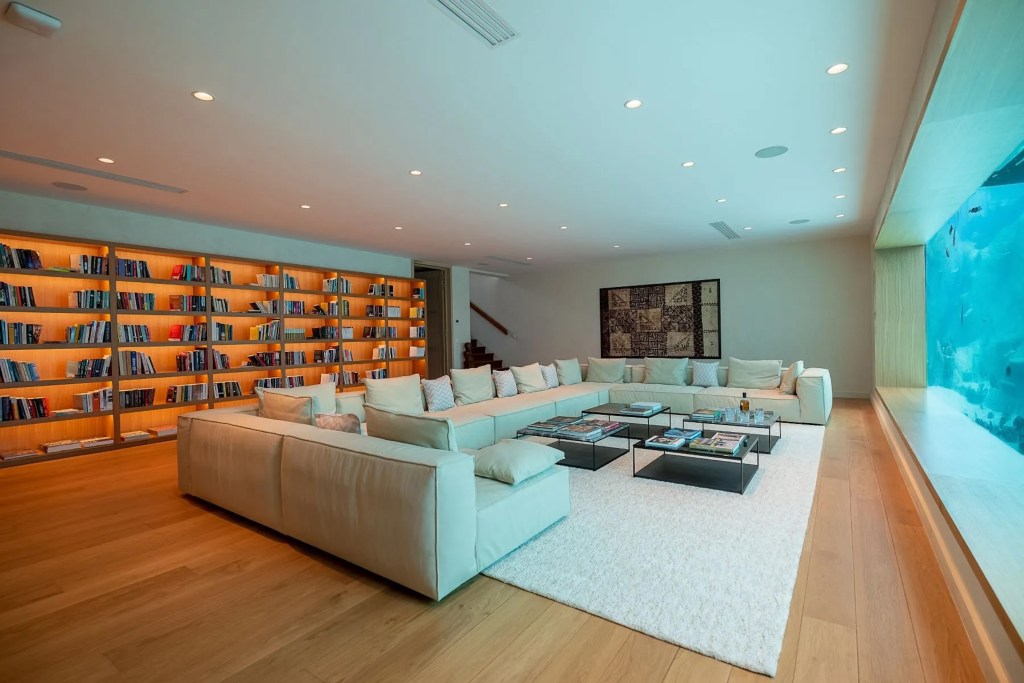 large u-shaped couch in Bora Bora villa salon, with large bookshelves in the background, facing an aquarium tank 