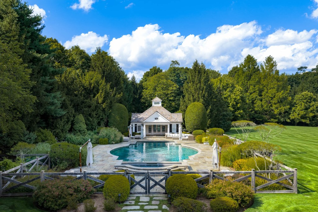 pool house in Greenwich, CT home, with Roman-style swimming pool and spa, lush landscaping, and wood fence