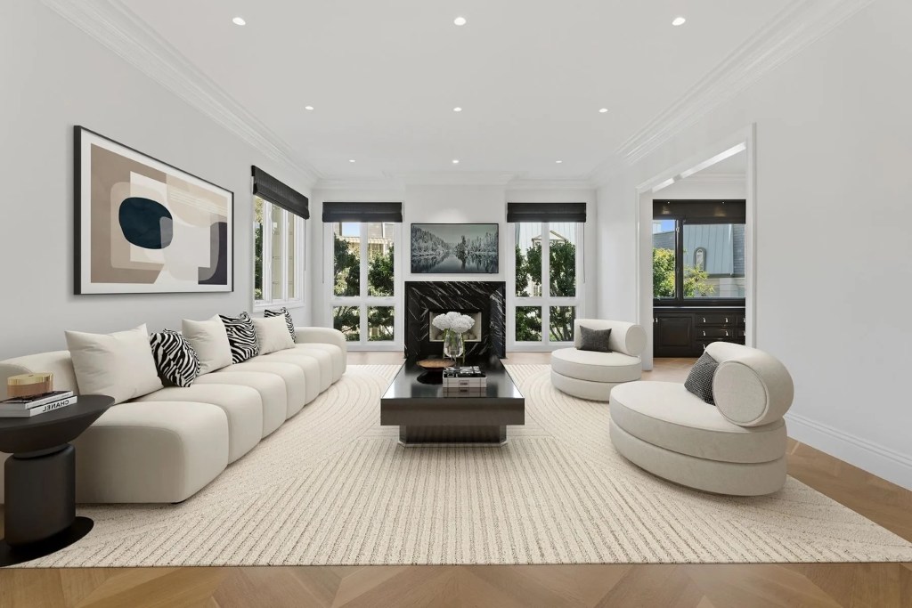 large monochromatic living room in Century City home, with black and white marble fireplace, abstract white sofa and chairs, large stone coffee table, and art on the walls in a black and white color palette