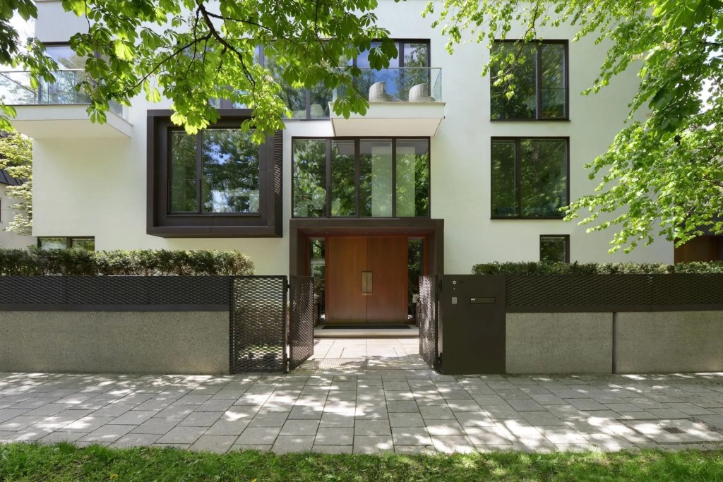 Exterior of three-level Maisonette in Munich, with gates and walls, brown wood doors, and windows looking out